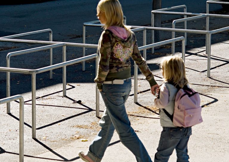 En vuxen och ett barn passerar metallräcket som inhägnar skolgården. Love and devotion, helhetsgestaltning av Olaus Petri-skolan