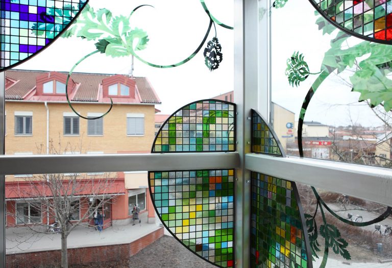 Glasruta med slingrande blommönster och en monterad skärm med bladformer i blyinfattat antikglas. Kristoffer Zetterstrand, In Vitro (2012)