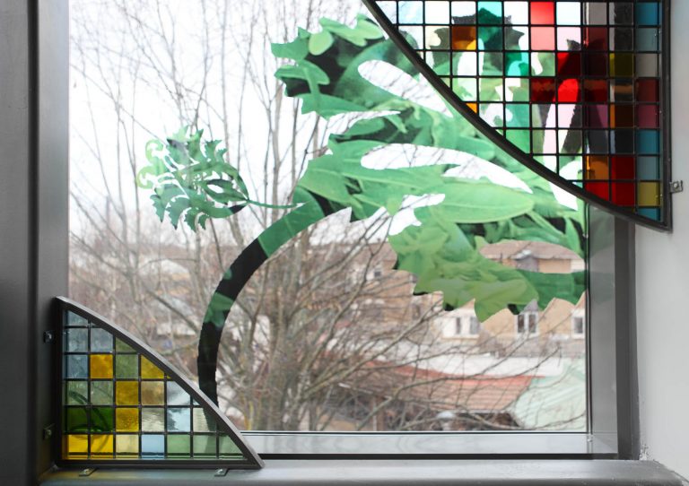 Glasruta med slingrande blommönster och monterade skärmar med bladformer i blyinfattat antikglas. Kristoffer Zetterstrand, In Vitro (2012)