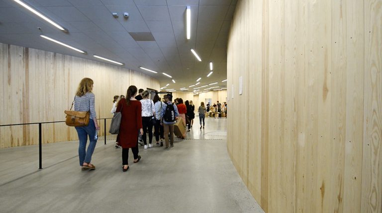En grupp studenter går genom en korridor med träpanel och lysrör i taket. Jonas Dahlberg An imagined city