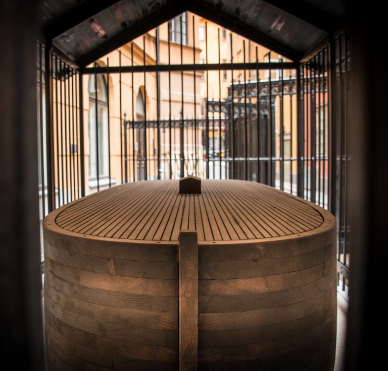 En övertäckt träbåt innanför ett galler. Jan Håfström Arken