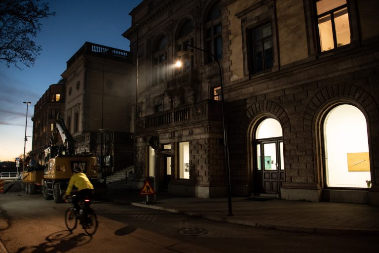 På fasaden till Konstakademien i Stockholm lyser lampan från verket Förhandlingen.
