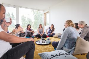 Människor sitter i en ring på golvet och samtalar.