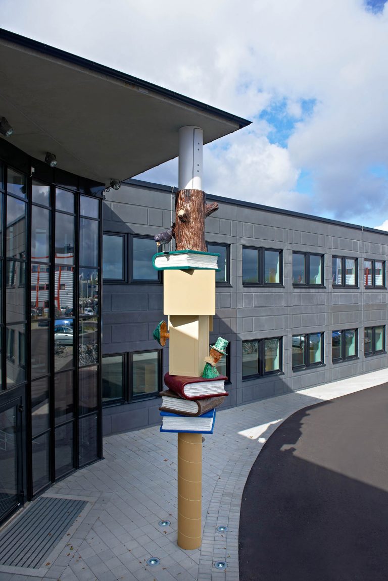 Skulptural pelare med färgglada böcker, kartonger och figurer gjutna i polyester. Daniel Jensen, Fundamentet (2012)
