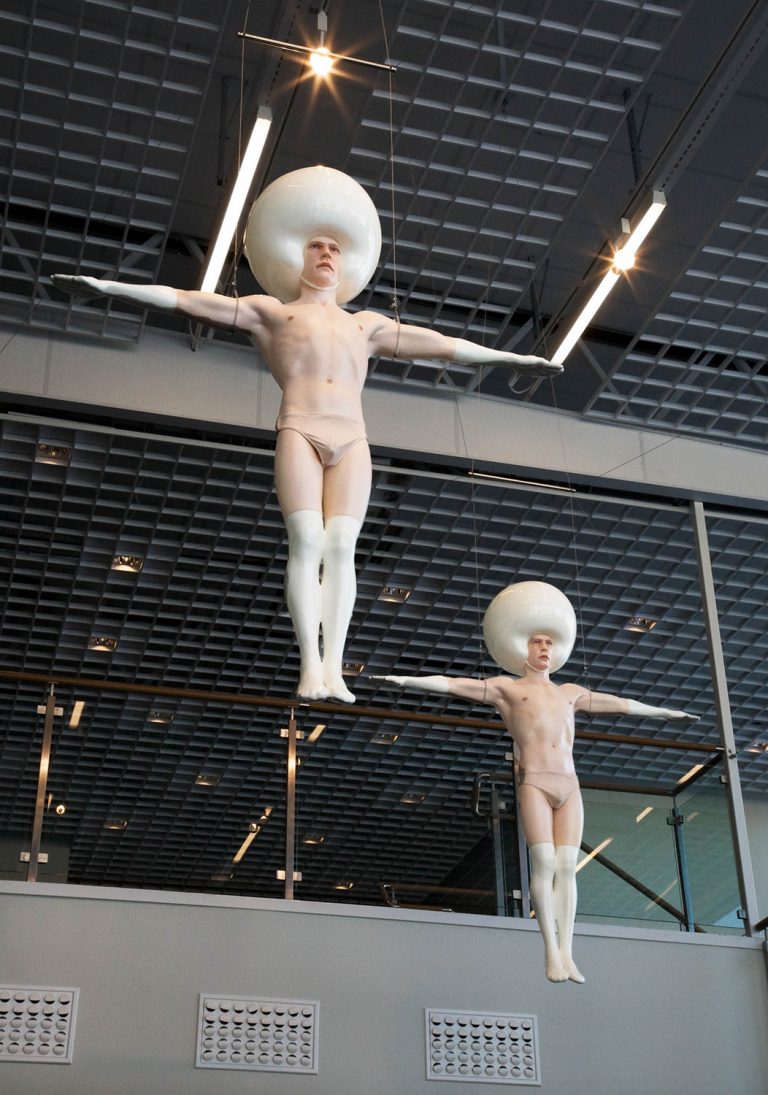 Två av skulpturerna sedda nerifrån med taket som fond. Klädda i vita strumpor och handskar. Christian Pontus Andersson, A Joyful Troop of Perfection, with crying sensitive hearts