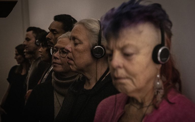 En rad människor står med hörlurar i en hall.