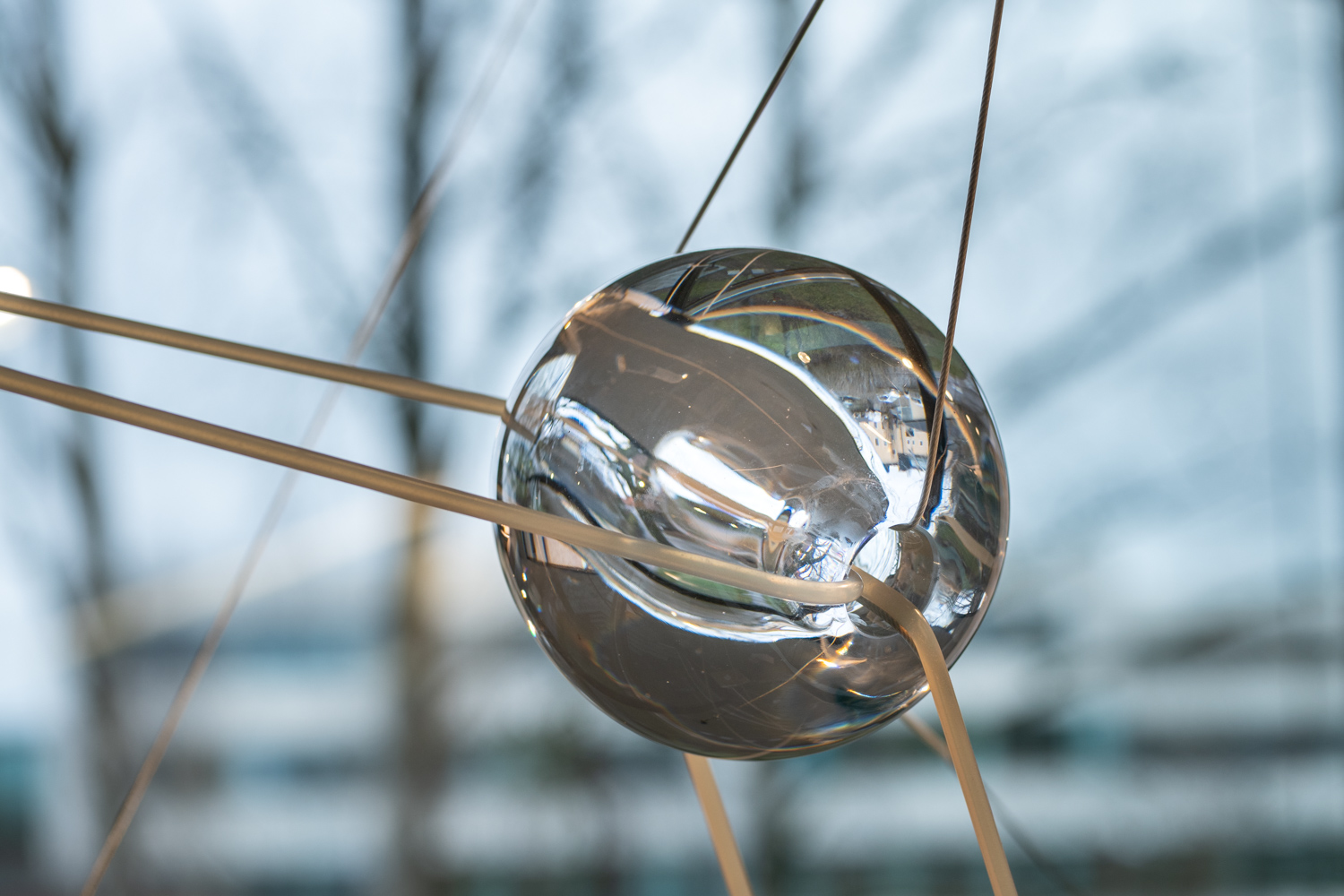 Handbllåsta glaskulor som svävar i gummitrådar i ett trapphus.