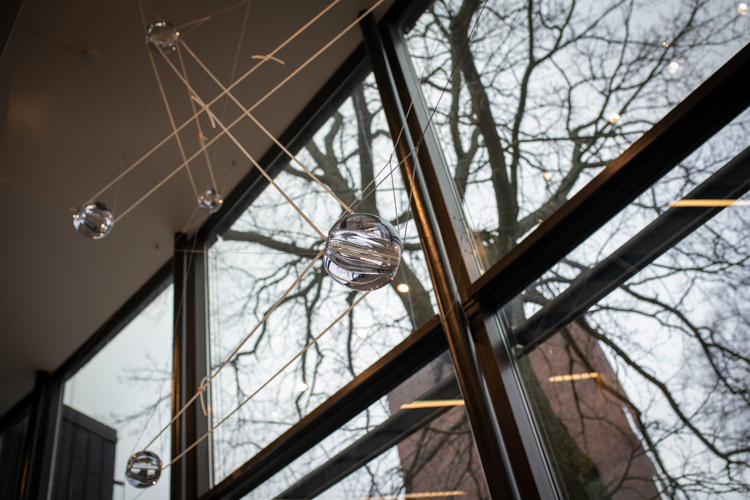 Handbllåsta glaskulor som svävar i gummitrådar i ett trapphus.