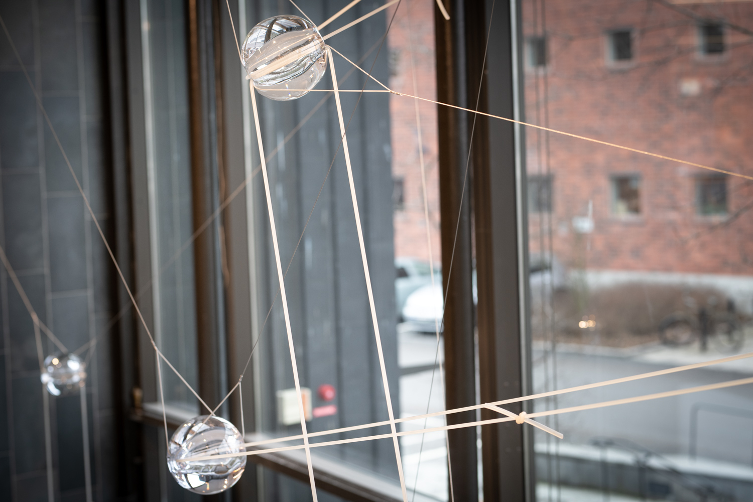 Handbllåsta glaskulor som svävar i gummitrådar i ett trapphus.