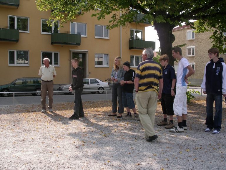 En grupp människor spelar boule utomhus.