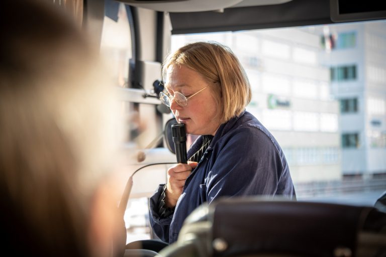 Kvinna pratar i en mikrofon på en buss