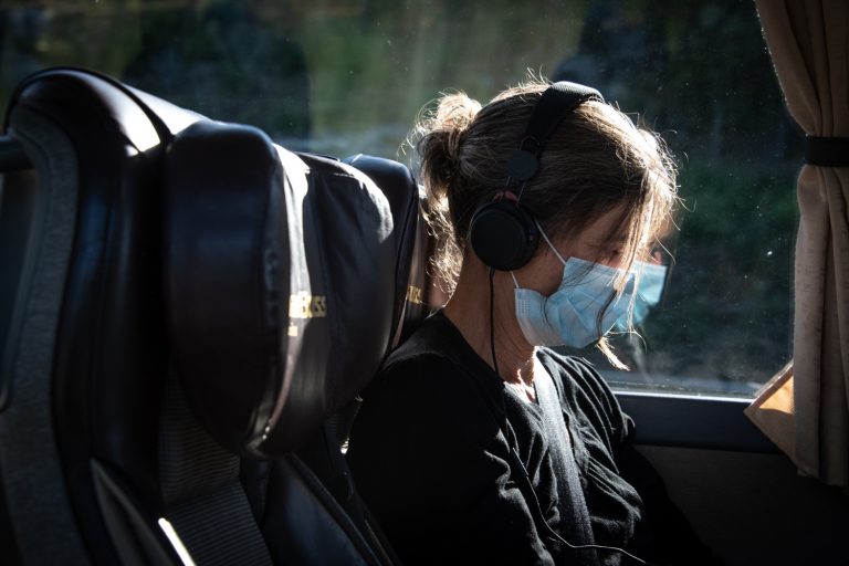 Person med munskydd och hörlurar på en buss