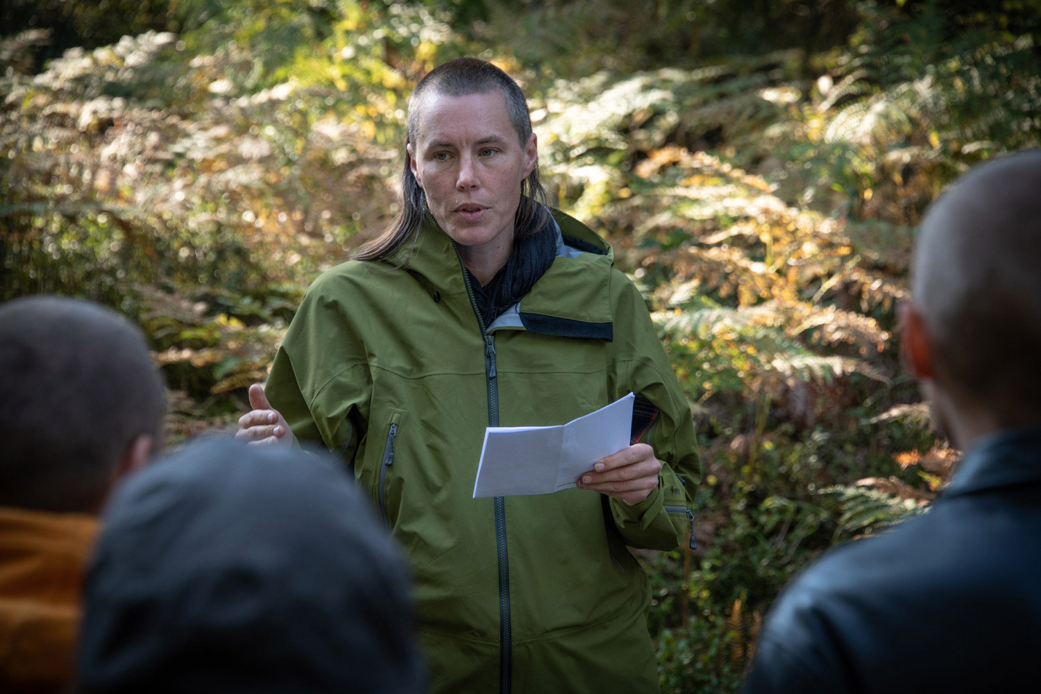 Person står i skogen med ett papper i handen