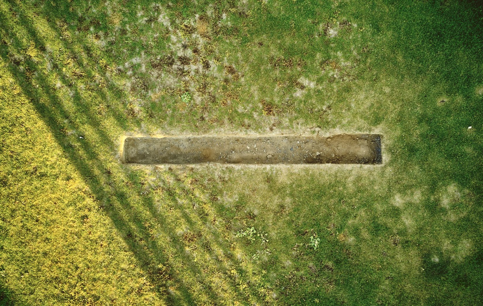 En gräsmatta som en långsmal grop har grävts i.