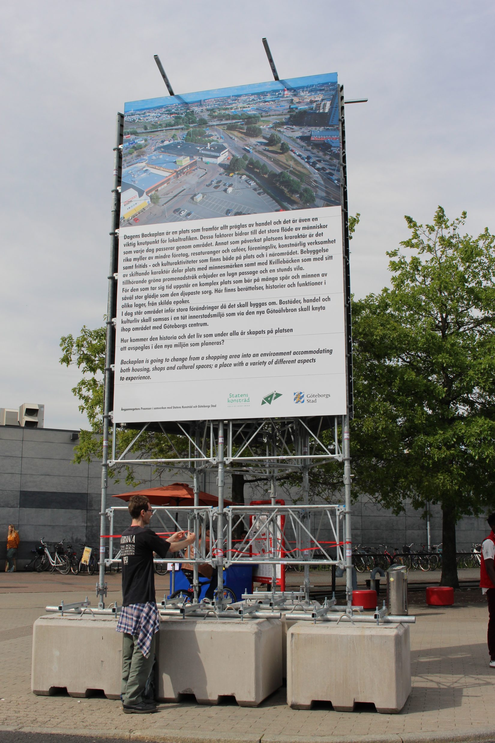 Man står under en stor skylt med bild och text