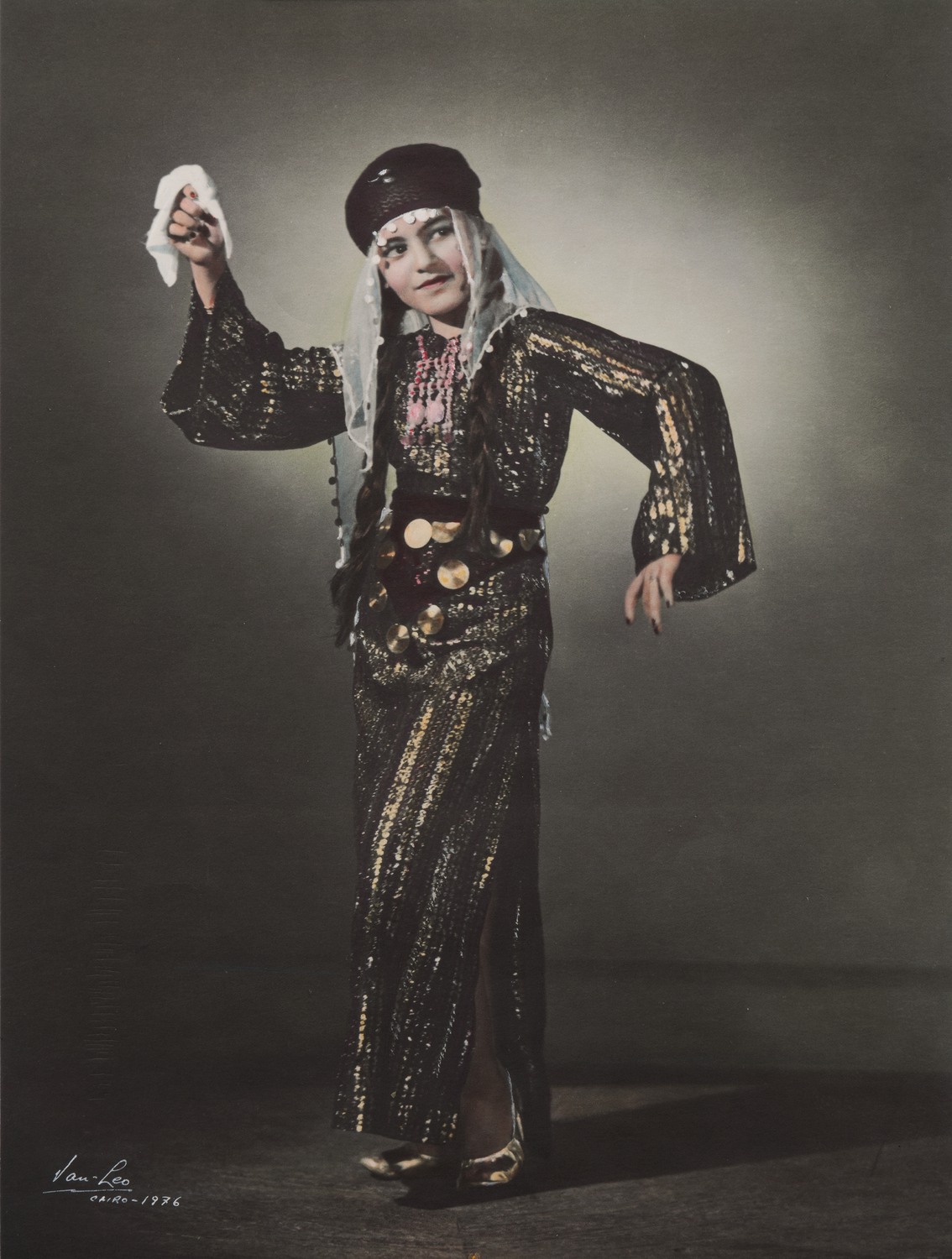 En kvinna i klänning och huvudbonad dansar med en näsduk