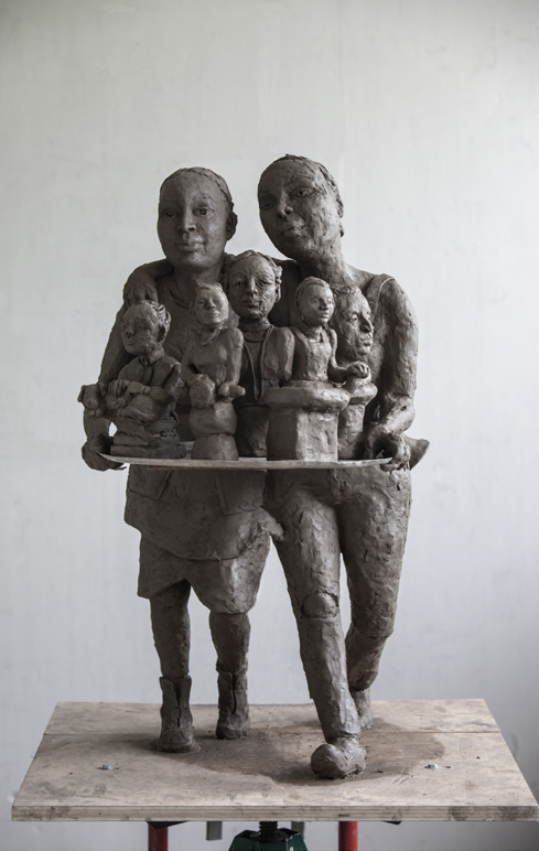 En skulptur av lera av två unga kvinnor som bär fram byster på fem kvinnor.