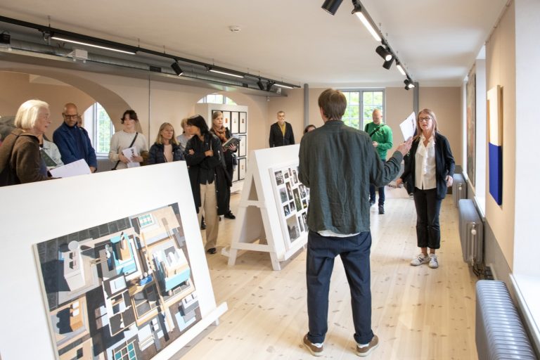 En grupp människor lyssnar på en curator i en utställningssal
