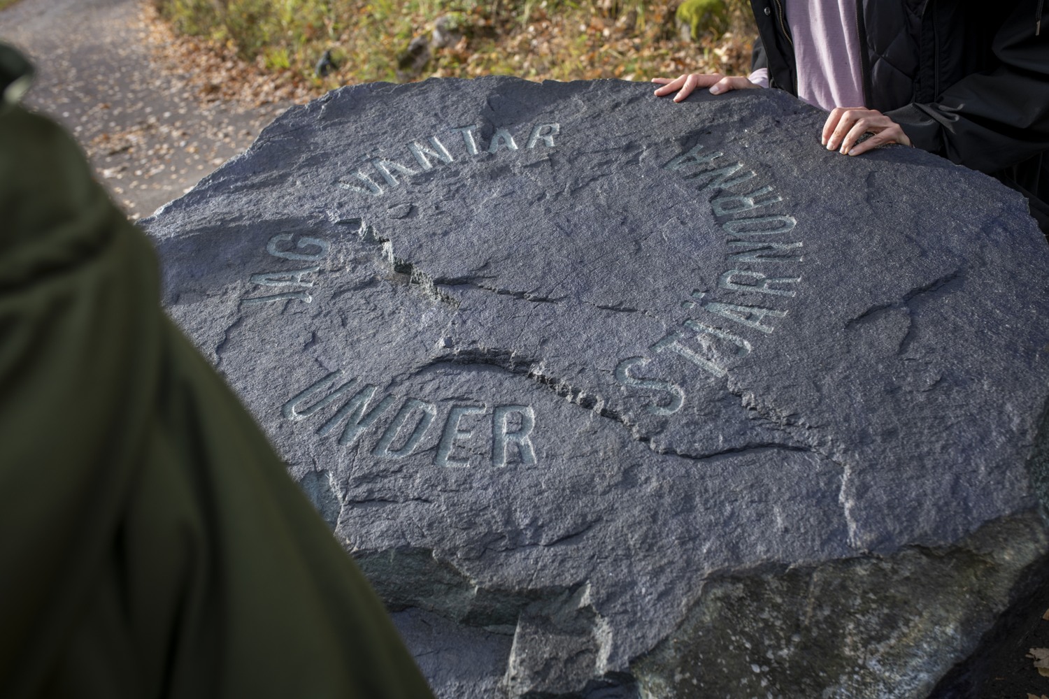 En sten med graverad text. Jag väntar under stjärnorna