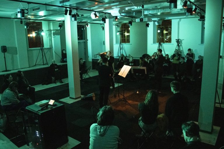 Bild på musiker och publik i ett mörkt rum