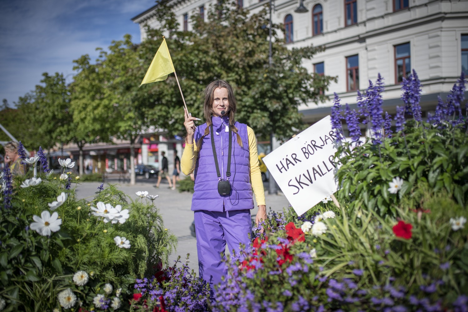 Kvinna står med en liten flagga framför ett blomhav