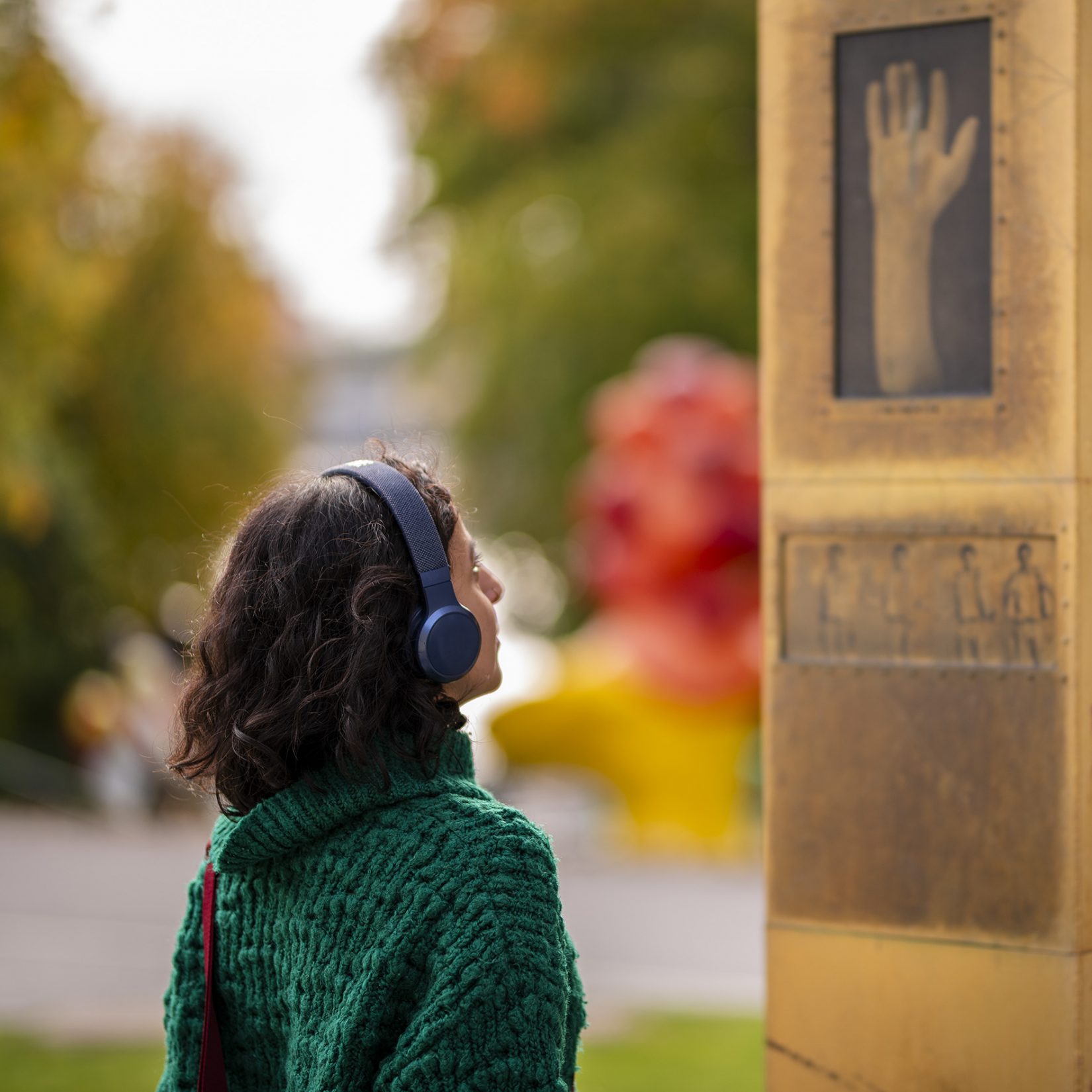 Kvinna tittar på ett verk och lyssnar med hörlurar.