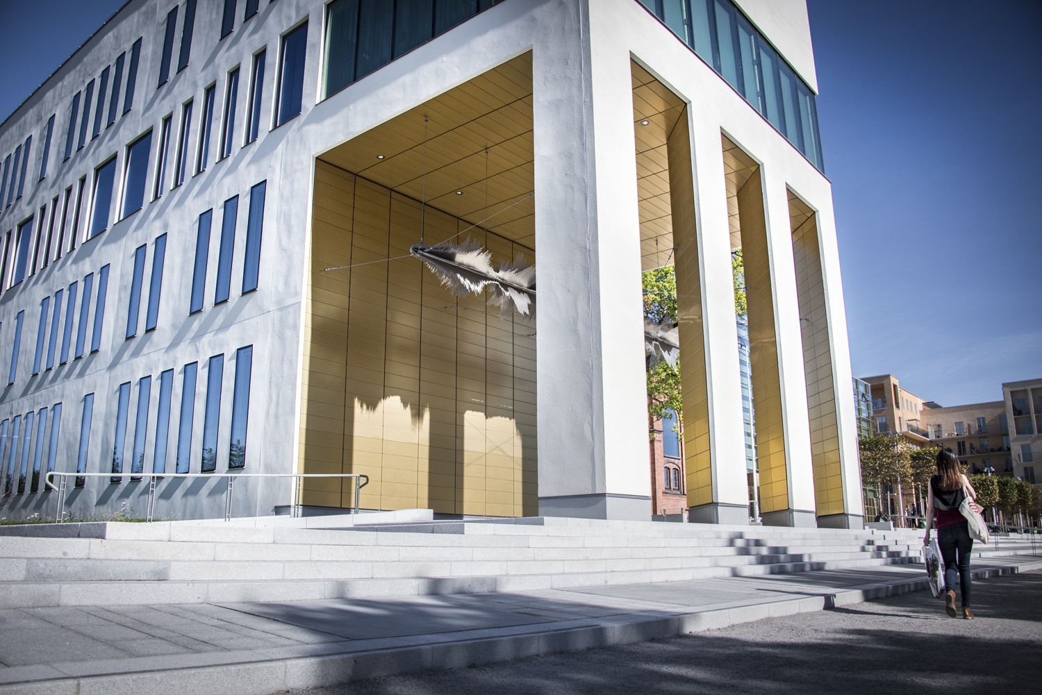 En kvinna som går förbi en hög byggnad med en fågel som flyger ut ur den