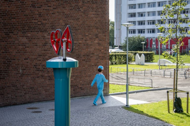 En liten pojke som går förbi en skulptur