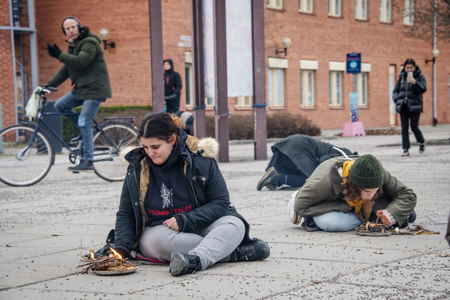 Personer som sitter på marken vi en eld