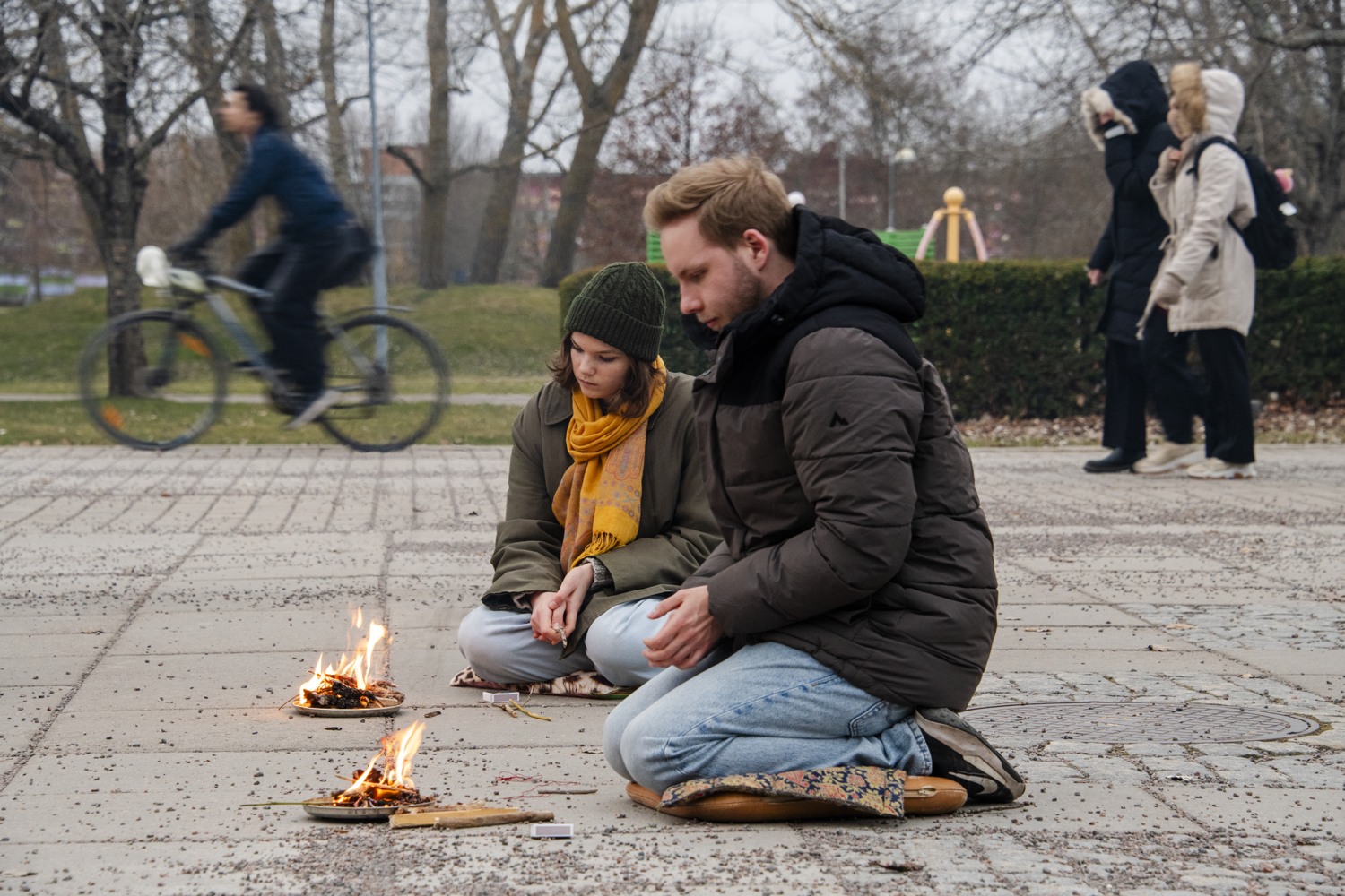 Två personer som sitter på marken vi en eld
