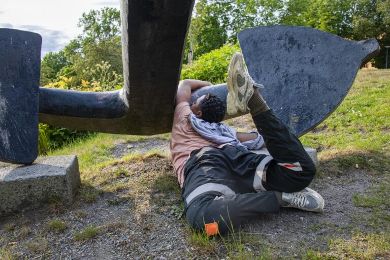 En man som ligger på marken bredvid en skulptur.