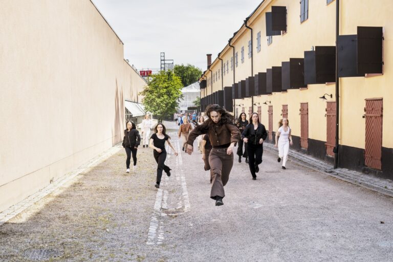 En grupp människor som går längs en gata bredvid höga byggnader.