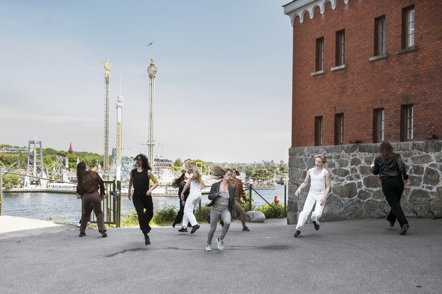 En grupp människor som går längs en gata bredvid en tegelbyggnad.