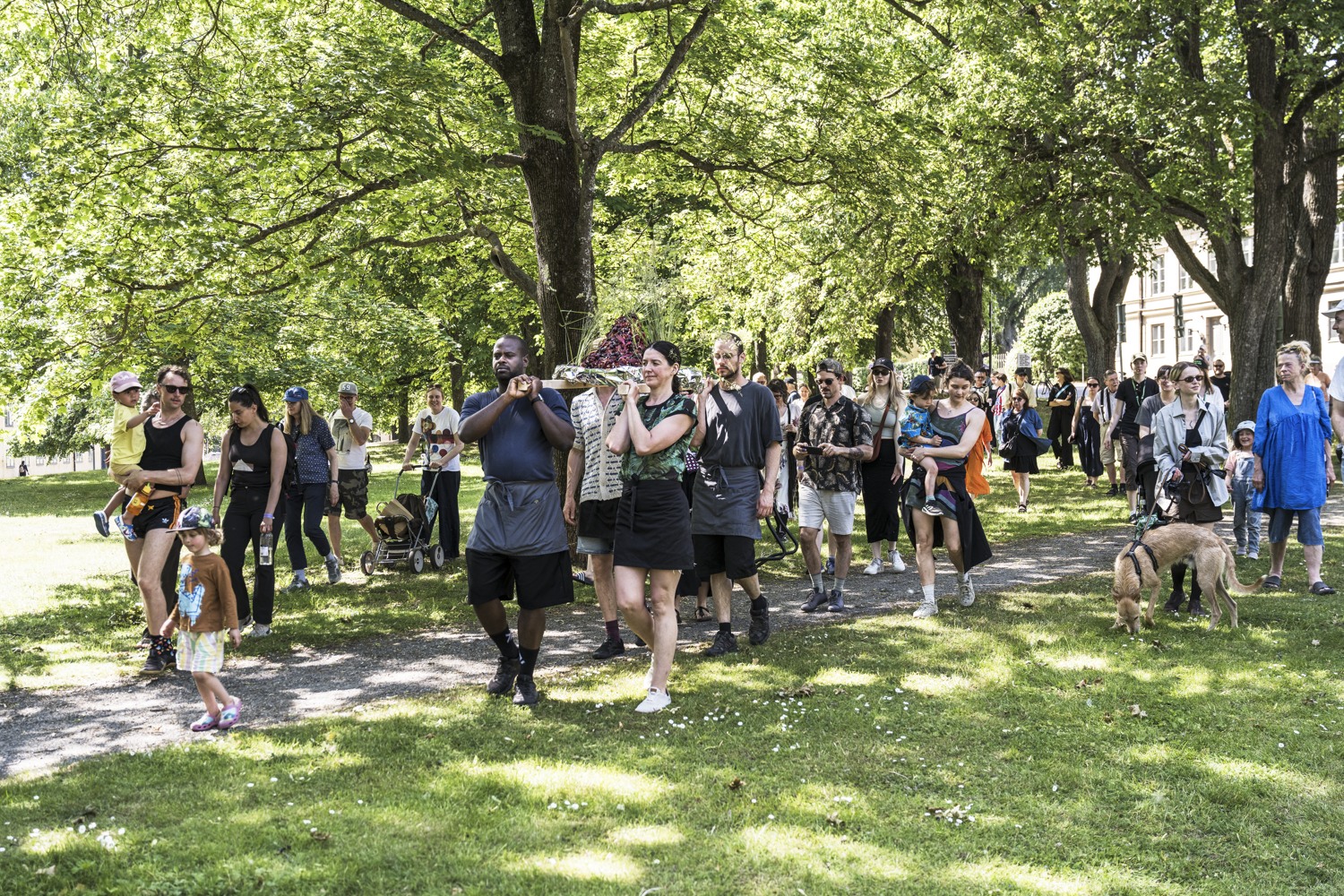 En stor grupp människor som går längs en trottoar.
