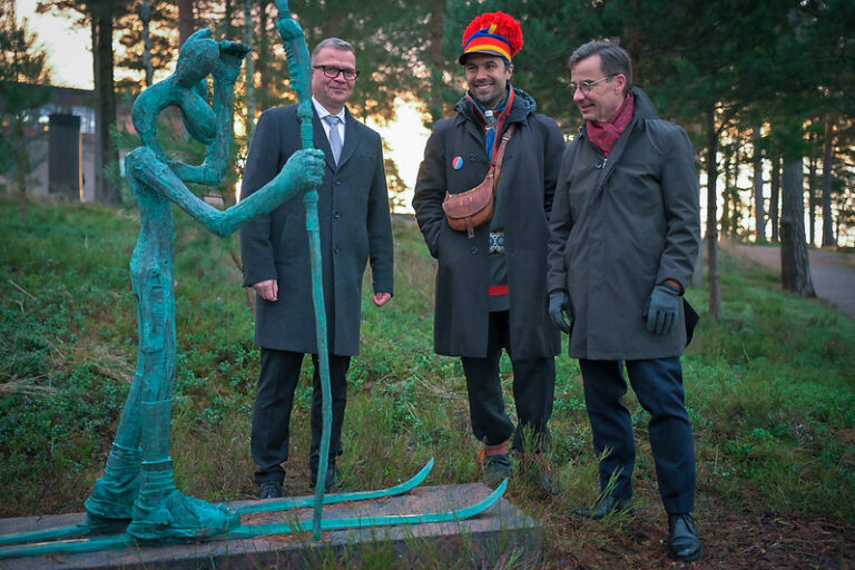 En grupp på tre män som står bredvid en staty.