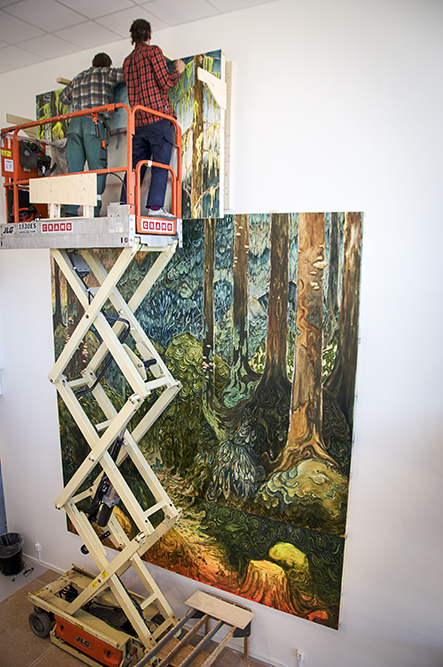 Två män med bygghjälmar i en skylift monterar överdelen av målningen på väggen. Danilo Stankovic, När fåglar tystna.