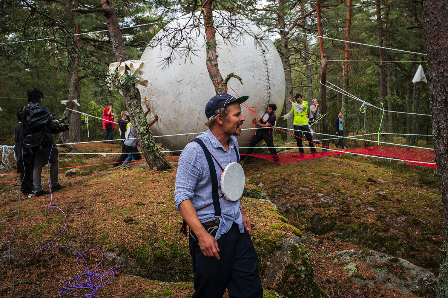 Människor i en skog rullar en stor boll.