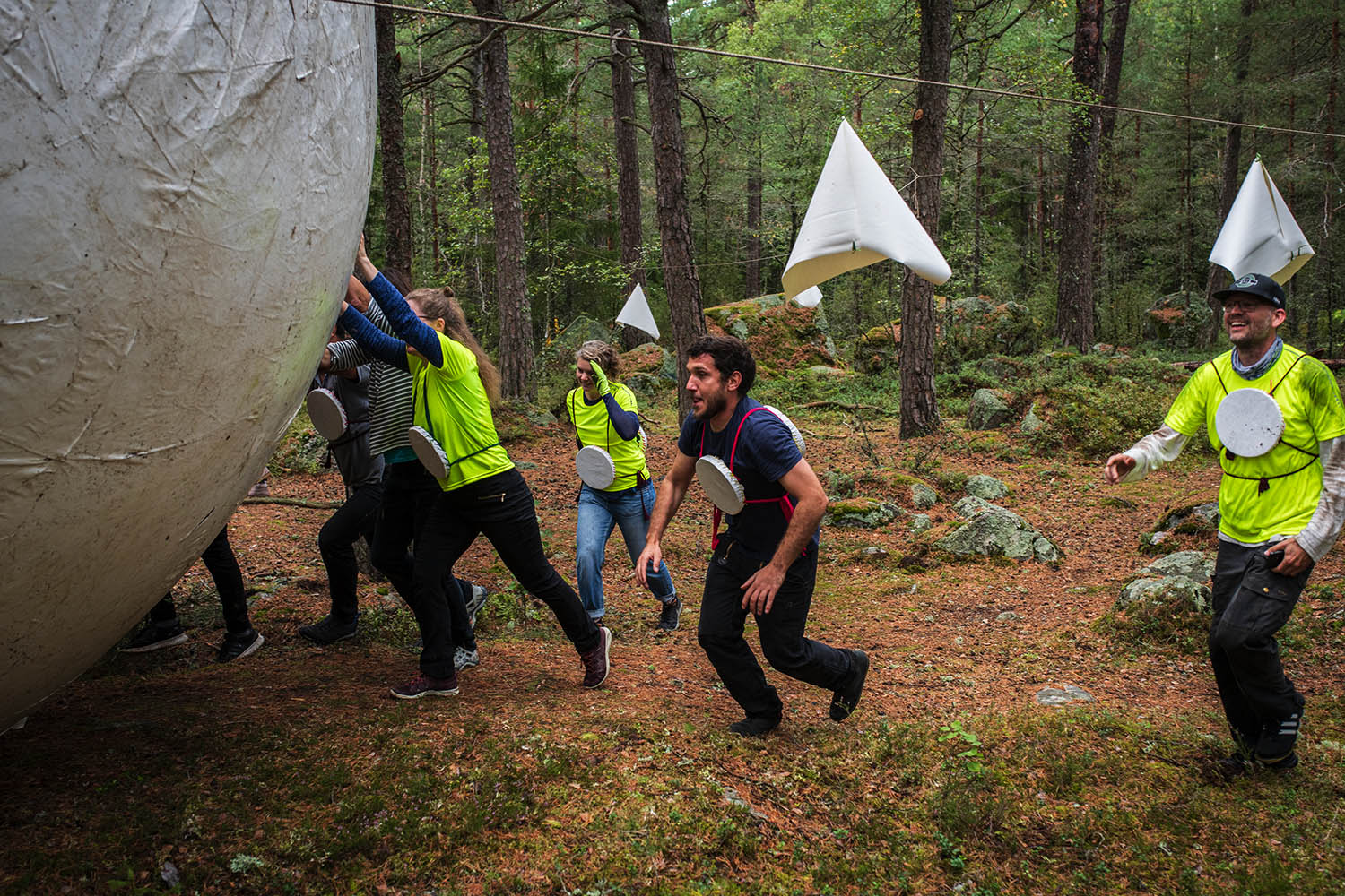 Människor i en skog rullar en stor boll.