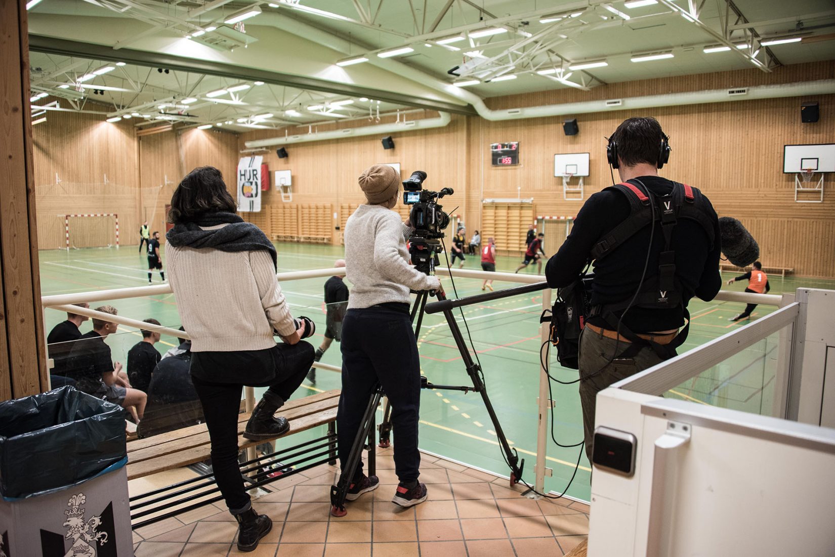 Ett filmteam på tre personer dokumenterar en fotbollsmatch.