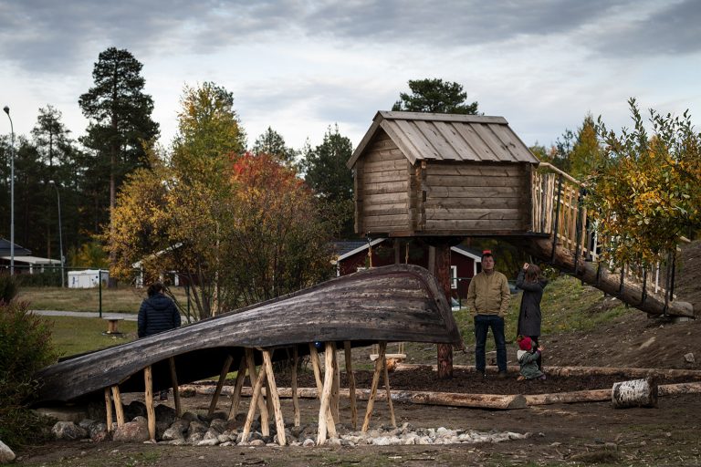 Föreskolegård med en båt uppallad på pinnar till vänster och en bod till höger.