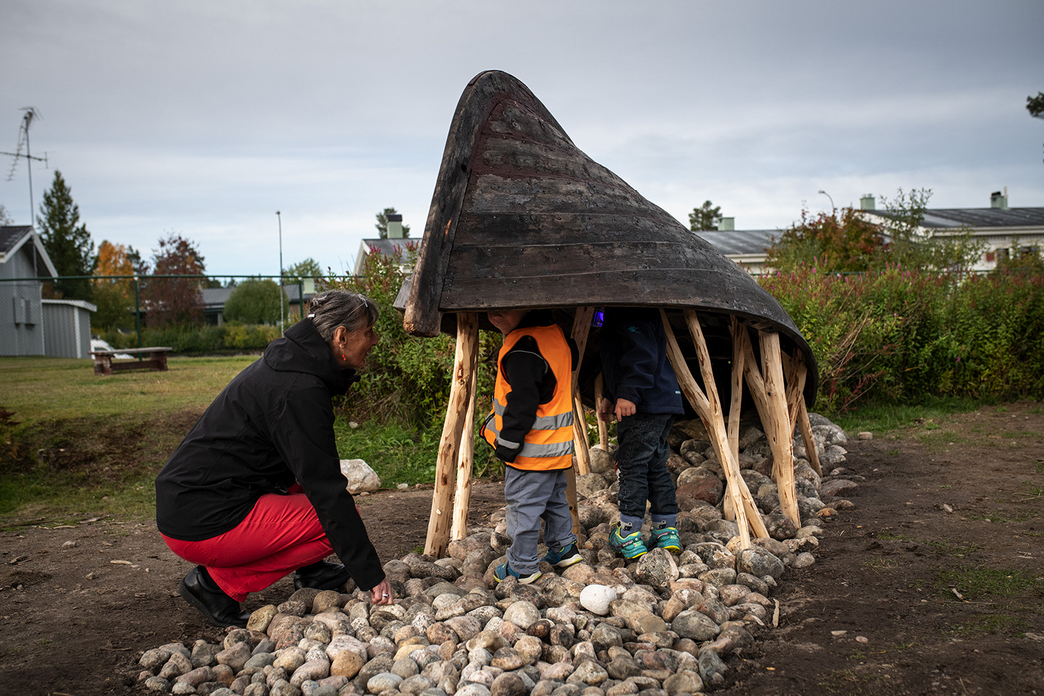 Barn som står under en båt och leker.