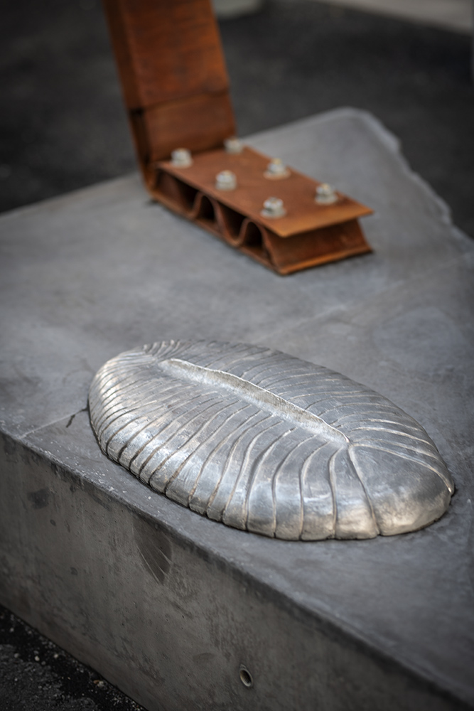 Detalj av metall som ser ut som en fossil på ett underlag av sten.