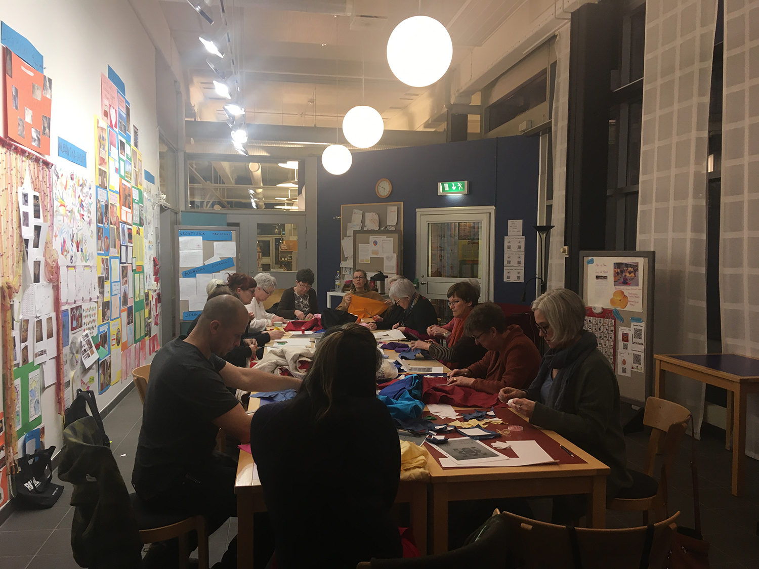 En samling personer sitter kring ett bord och arbetar.