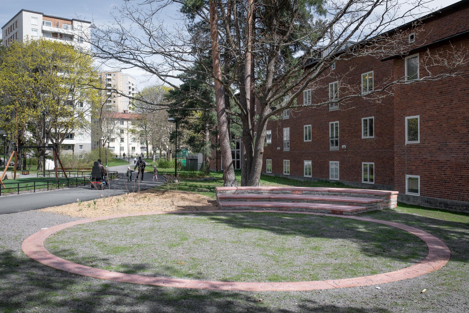 En ring av stenplattor är placerad framför en sittplats av tegel och stenplattor.