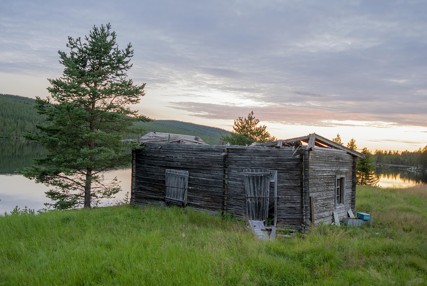 En gammal övergiven stuga stå vid ett vattendrag.