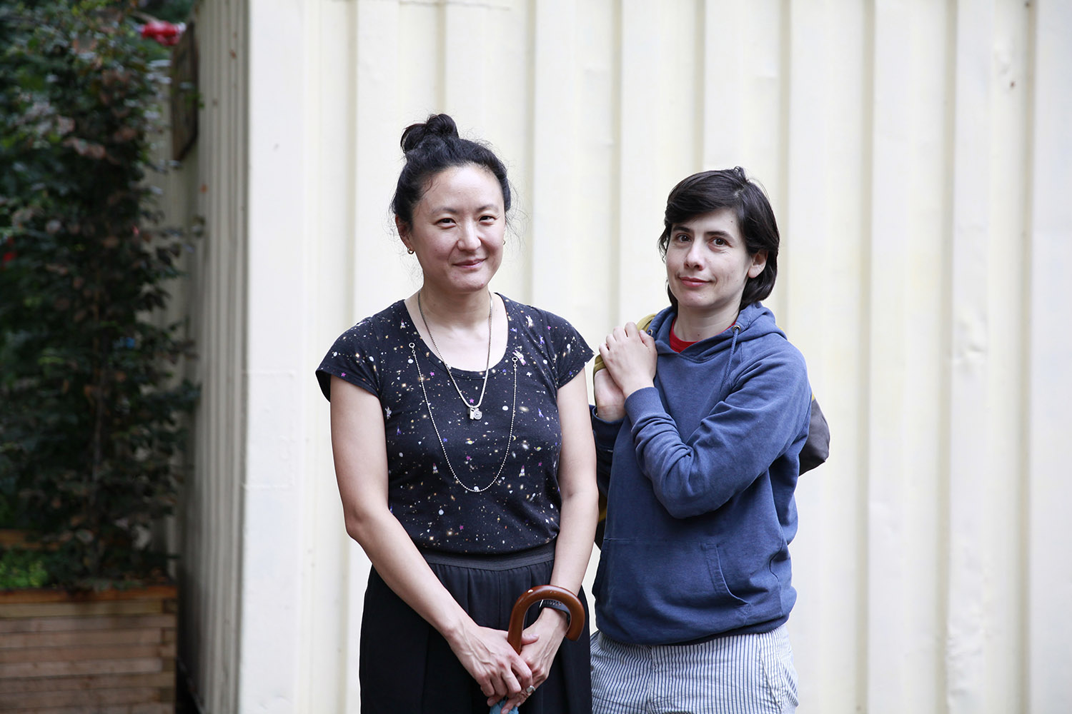 Två kvinnor framför en vit husvägg