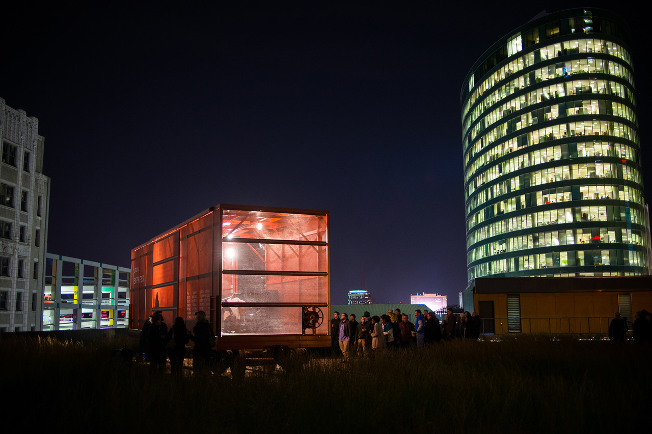 Bild tagen på natten av upplyst röd godsvagn i gräs framför en skyskrapa