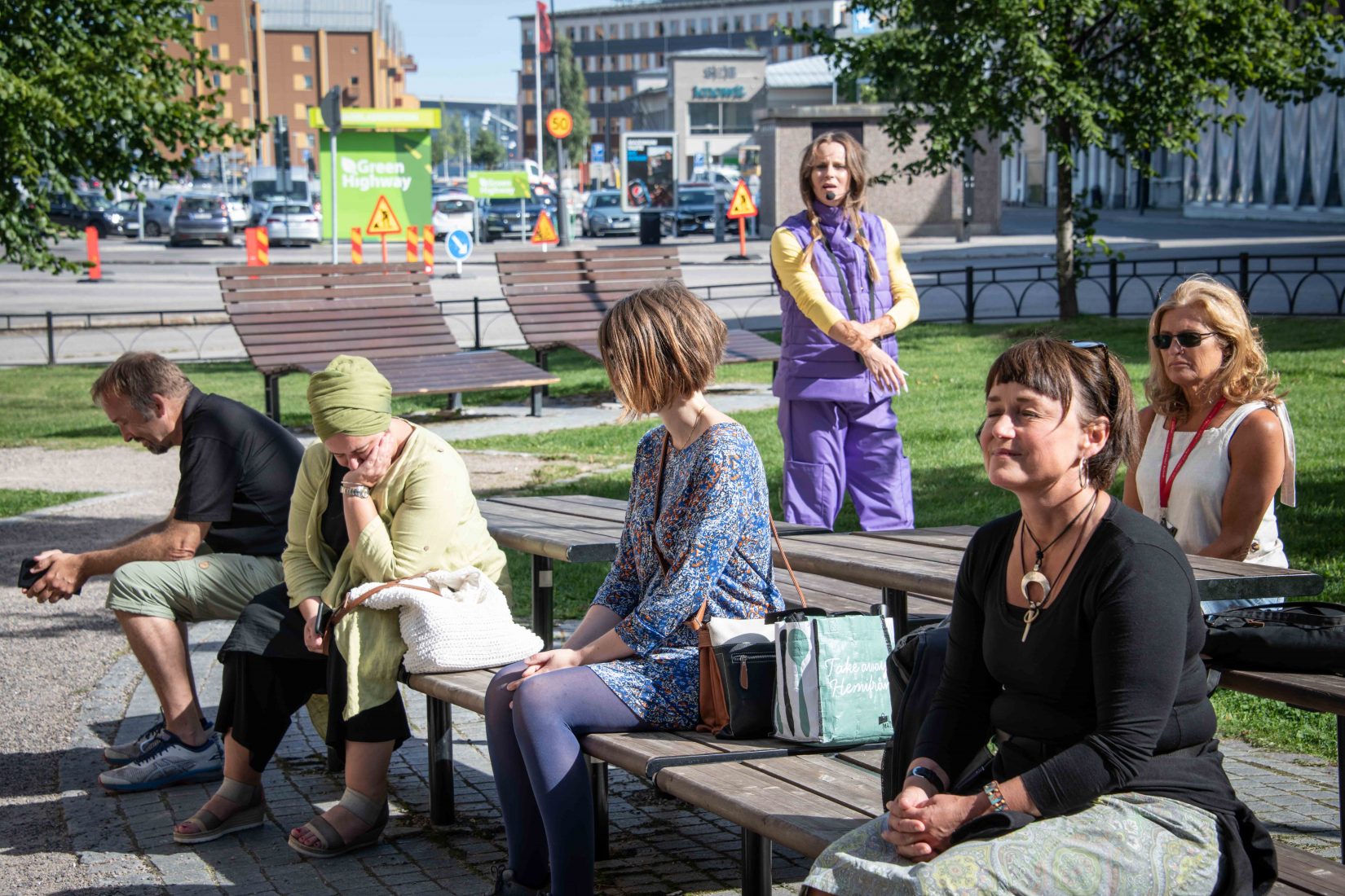 Människor som sitter på bänkar i torg i stad.