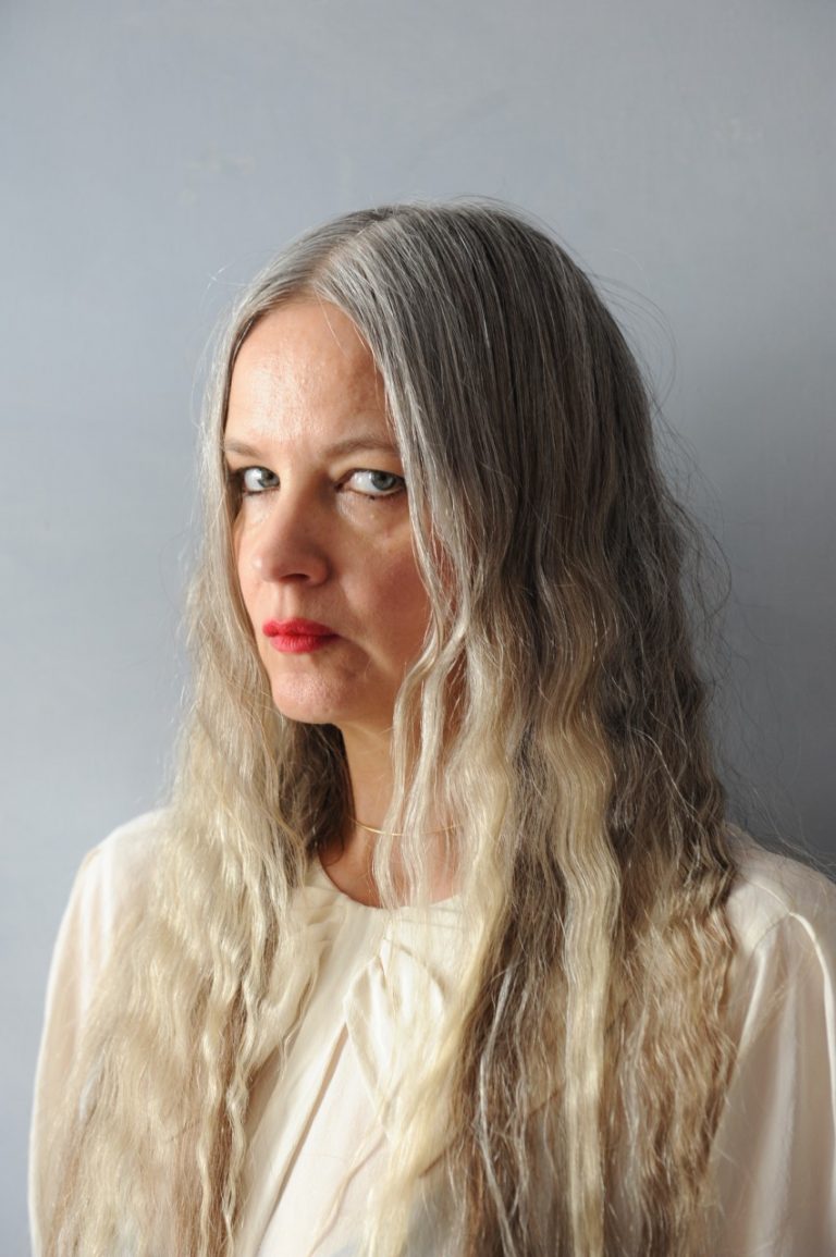 Porträtt på en kvinna mot en grå bakgrund.