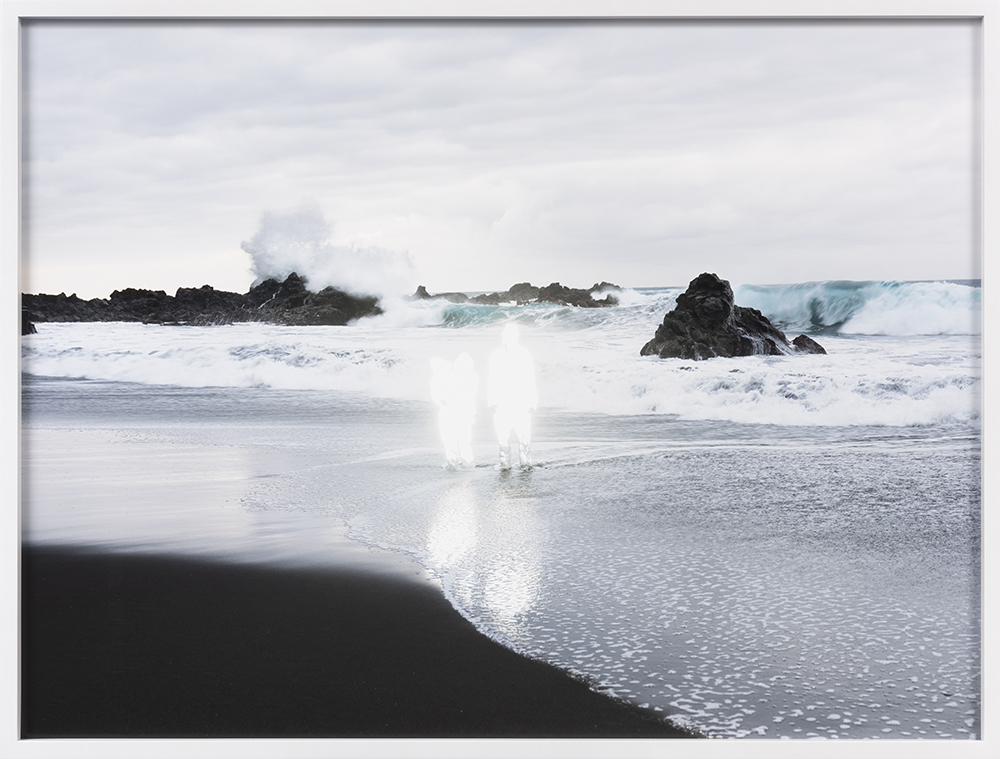 Tavla som visar en strand där vågor slår in och två figurer av ljus finns i mitten.